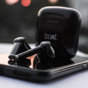 Sleek black wireless earbuds on a smartphone with a blurred outdoor background.