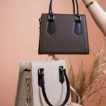 Display of two stylish handbags with a natural backdrop in a studio setting.
