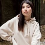 A young woman in a hoodie poses thoughtfully in a bamboo grove, Ciudad de México.