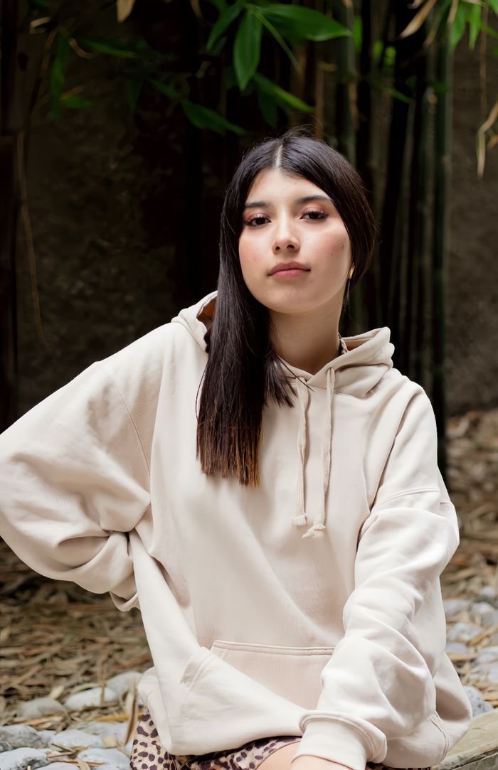 A young woman in a hoodie poses thoughtfully in a bamboo grove, Ciudad de México.